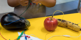 Students work on a fruit piano in a school makerspace.